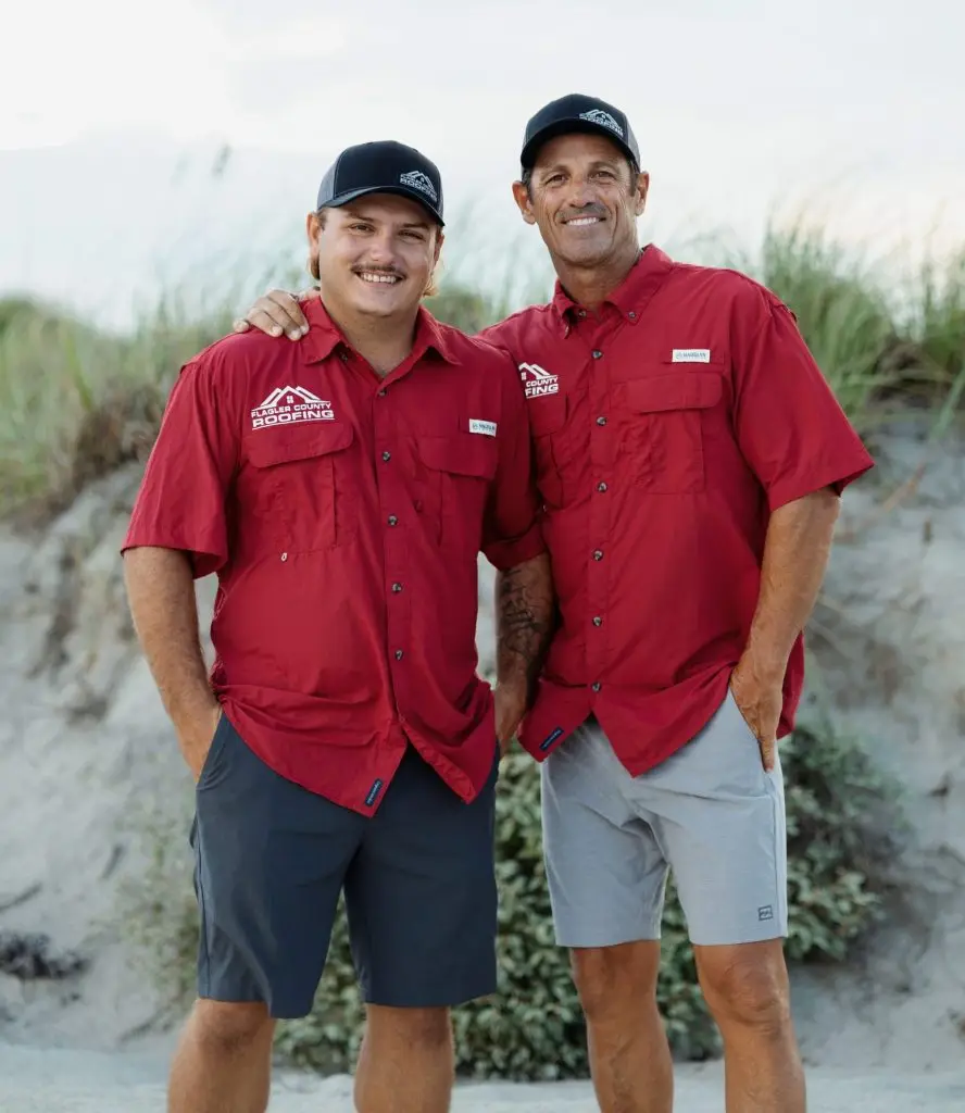 Owners Dan Provenzano and CJ Barbosa standing on the beach against the dune.